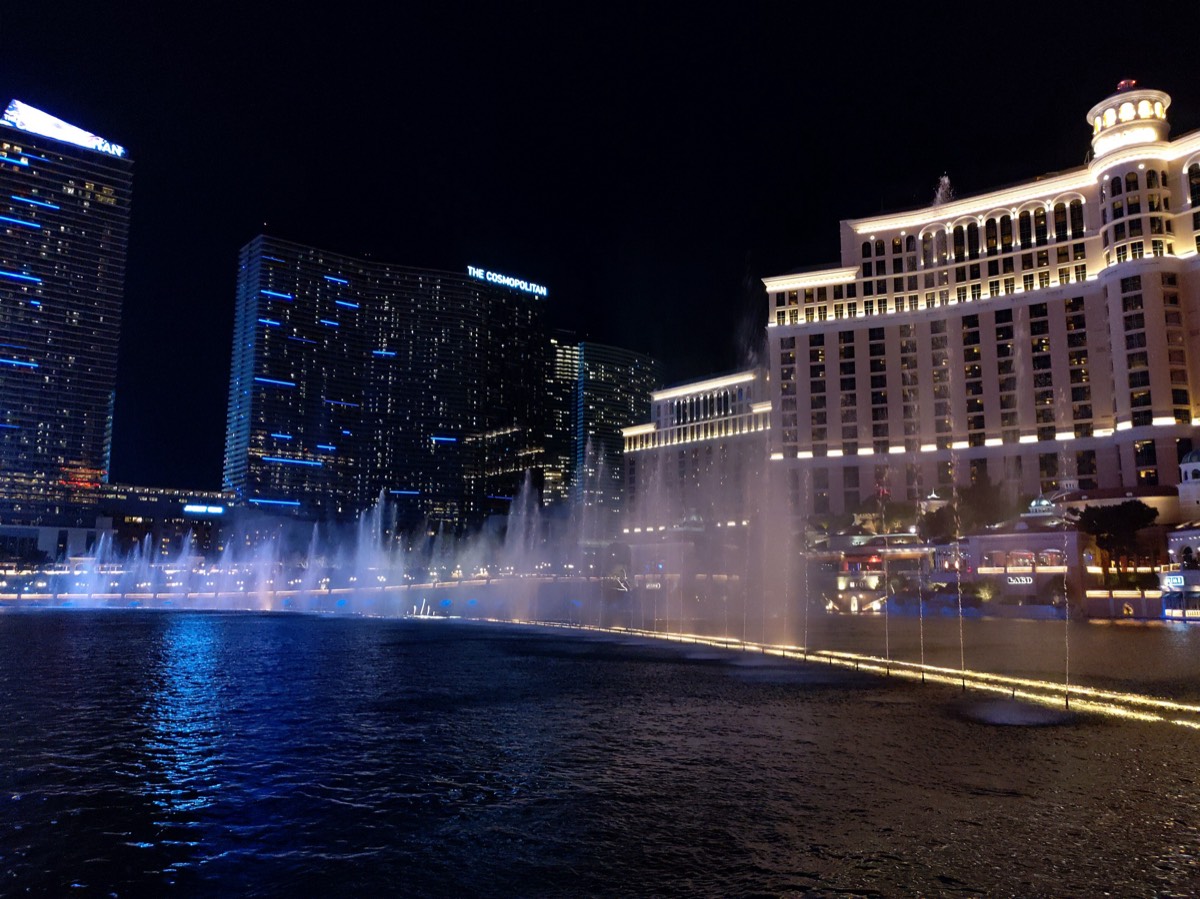 Bellagio音乐喷泉夜景,水柱喷起,远处Cosmopolitan与Aria